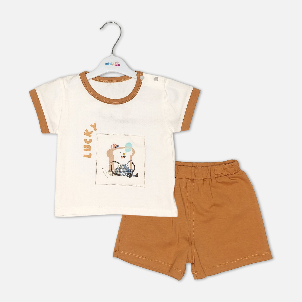 boysSuit14172-1-1 Toddler boy 2-piece summer clothing set featuring an off-white t-shirt with a "Lucky" cartoon toast graphic and tan trim details, paired with matching tan elasticated shorts from Mini & Me.