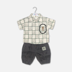 Mini and Me boys two piece summer suit set hanging on a white hanger, featuring a cream short sleeve button down shirt with a green checkered grid pattern and a cartoon bear chest pocket graphic, paired with matching textured charcoal grey shorts featuring a small square number patch, displayed on a light gray background in file 20-1_2.jpg.