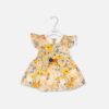 A premium baby girl summer dress in a warm cream color printed with yellow, orange, and blue watercolor flowers, featuring ruffled flutter sleeves and a yellow waist ribbon adorned with navy, orange, and gold fabric blossoms.