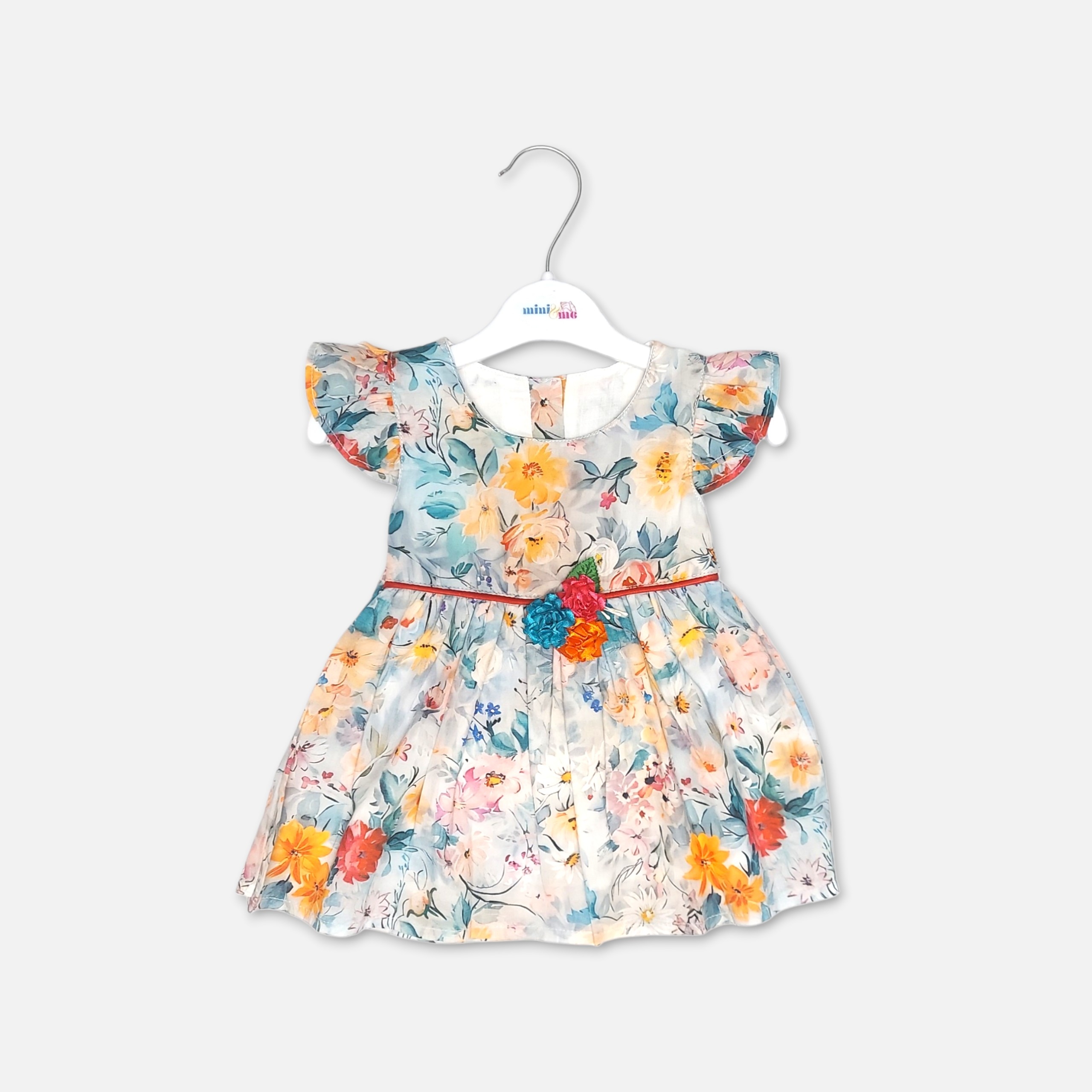 20260711_162106 (5) Mini and Me baby girl multicolor watercolor floral frock with blue yellow and orange flowers and a 3D fabric flower accent on the waist hanging on a white hanger