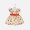 Baby girl off-white cotton frock with red floral prints, ruffle sleeves, and a red waistband with a yellow fabric flower hanging on a white hanger.