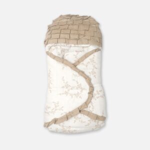 A premium newborn swaddle wrap and sleeping bag featuring a cream fabric with a beige botanical branch print, a layered taupe ruffle hood, and an overlapping front closure with matching ruffled trim borders, laid flat.
