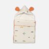 A premium convertible cream-colored baby carry nest with a terracotta trim and backing, featuring a minimalist scattered print of blue airplanes, grey helicopters, and small cars across the lower blanket section.