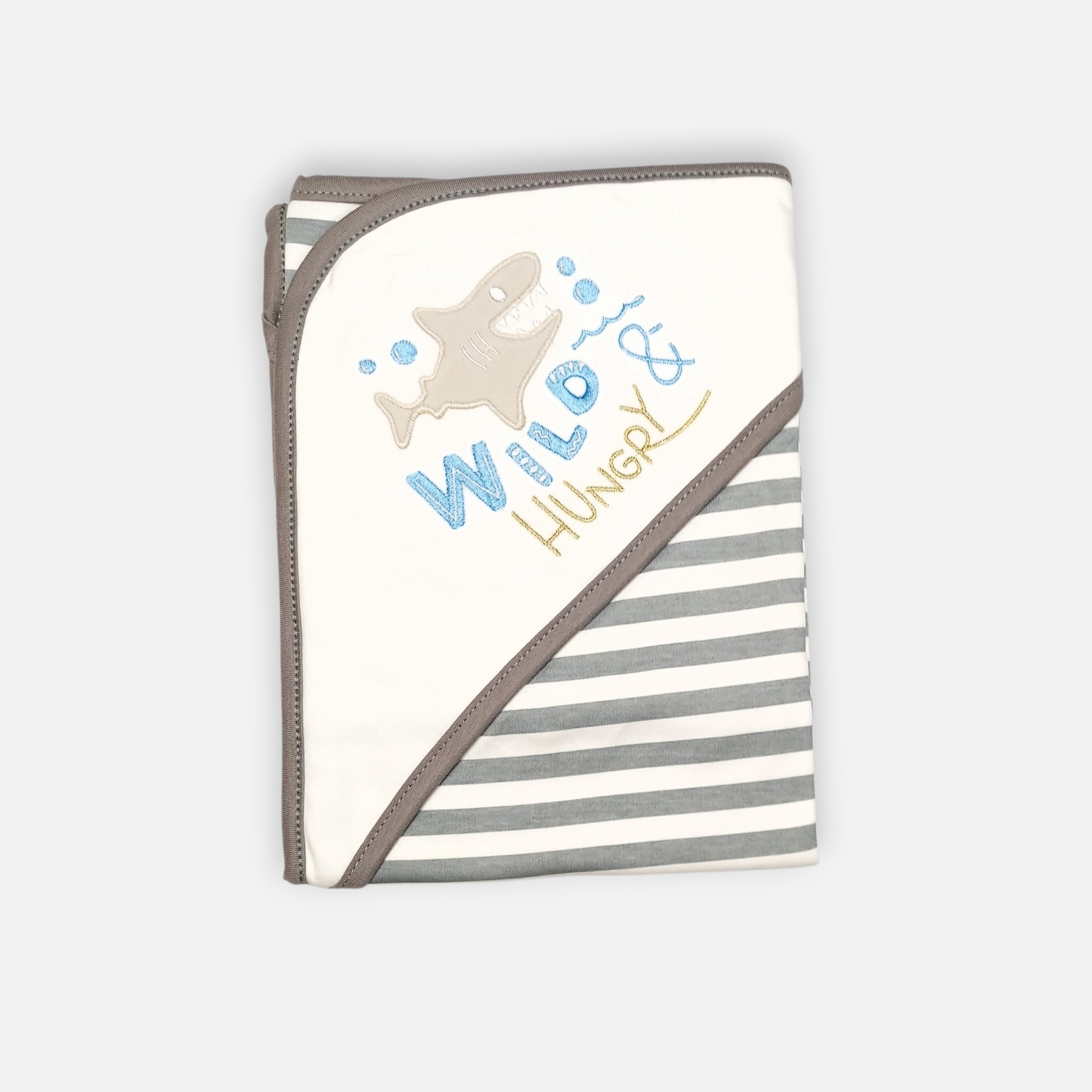 20260720_180530 (6) A folded grey and white 100% cotton hooded baby blanket featuring an embroidered shark graphic with the text "Wild & Hungry" on the solid white corner hood and a repeating horizontal grey and white striped pattern on the main fabric body.