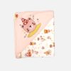A folded light peach and cream hooded baby blanket featuring an embroidered pink bear wearing a red and white polka dot party hat on the hood, next to a printed pattern of circus horses, elephants, and stars on the body.