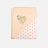 A folded peach and white 100% cotton hooded baby blanket featuring an embroidered swan design on the solid corner hood and a repeating small peach star print on the main fabric section.