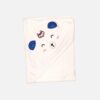 A folded off-white 100% cotton hooded baby blanket featuring a corner hood designed as a sleeping bear face with embroidered eyes, nose, whiskers, dimensional blue fabric ears, and a small embroidered fox motif.