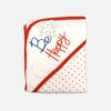 A folded off-white hooded baby blanket featuring a red polka dot pattern on the body, with a solid hood detailed with red trim and a colorful embroidered smiling star with the text "Be Happy."