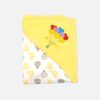 A folded yellow and off-white hooded baby blanket featuring a repeating hot air balloon print on the body, with a solid yellow hood detailed with a colorful embroidered bunch of heart balloons and the text "BE HAPPY."