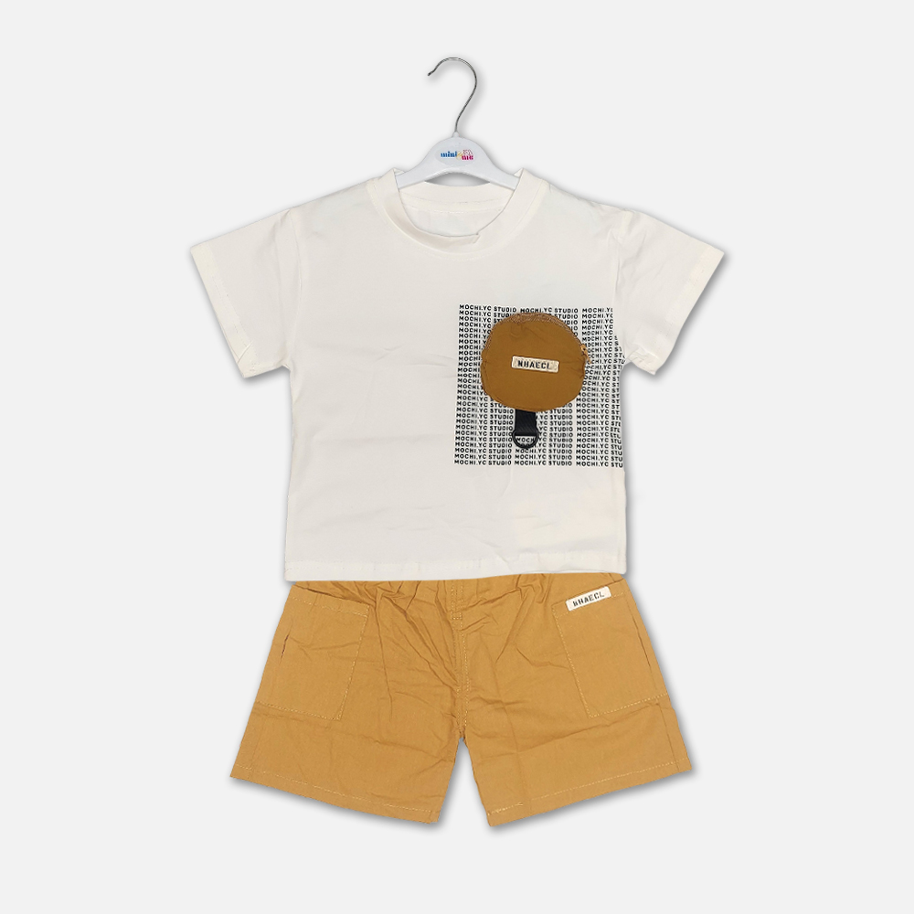 22-2 Mini and Me boys two piece summer casual suit set hanging on a white hanger, featuring a cream short sleeve crewneck t-shirt with a black typographic block print and a decorative brown circular pouch, paired with matching mustard yellow cotton shorts with an elastic waist, displayed on a light gray background.