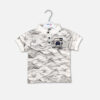 A toddler boys' short-sleeve polo shirt featuring an off-white and gray marble print texture, a white ribbed collar with three black buttons, and a circular City Life graphic patch on the chest, hanging on a white hanger against a gray background.