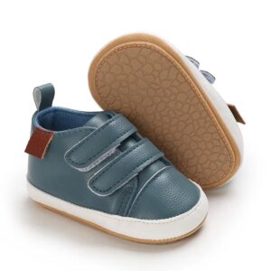 Slate blue faux leather baby pre-walker shoes showing one shoe with dual hook-and-loop straps, a white midsole, and a brown side tag, alongside the other shoe flipped to display the tan, pebble-textured non-slip soft sole.