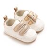 Pair of white faux leather baby pre-walker sneakers featuring dual adjustable metallic gold hook-and-loop straps, a metallic gold heel collar, a gold pull tab, and a flexible tan-bordered soft sole.