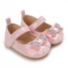 Glossy pink baby girl shoes featuring a rhinestone butterfly bow embellishment and an adjustable hook and loop ankle strap, displayed against a clean white background.