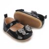 Shiny black patent leather baby girl Mary Jane shoes with a glittering rhinestone bow and textured flexible soles from Mini and Me.