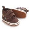 Pair of brown corduroy and faux leather high-top baby sneakers featuring dual hook-and-loop straps, embroidered tractor and snail illustrations on the side, a white sole border, and a textured non-slip dotted brown outsole.