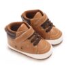 Pair of tan faux leather high-top baby sneakers with dark brown padded ankle collars, brown elastic laces, a single hook-and-loop strap, metal side eyelets, and a white sole border.