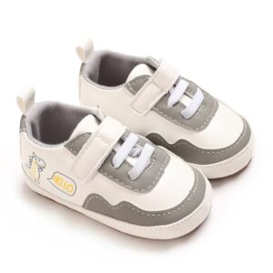 Pair of white faux leather baby pre-walker sneakers with grey accents, white elastic laces, an adjustable strap, a soft grey fabric lining, and a cute cartoon dinosaur graphic with a yellow hello speech bubble on the side.