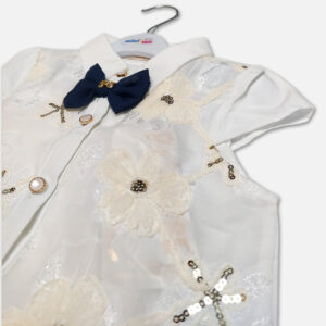A premium two-piece baby girls clothing set featuring a white cap-sleeve button-down shirt with embroidered flowers, sequins, and a navy bow tie, alongside a pleated navy blue skirt with silver stripes and a metallic gold belt, displayed on a hanger.