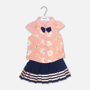 A luxury two-piece baby girls clothing set featuring a short-sleeve peach button-down shirt with embroidered flowers, sequin details, and a navy blue bow tie, alongside a pleated navy blue skirt with horizontal metallic stripes and a gold belt, displayed on a hanger.