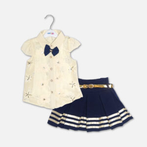 A premium two-piece baby girls clothing set featuring an off-white cap-sleeve button-down shirt with embroidered flowers, sequins, and a navy bow tie, alongside a pleated navy blue skirt with gold stripes and a metallic gold belt, displayed on a hanger.