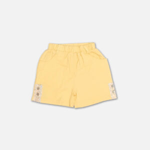 A premium two-piece summer clothing set for baby girls featuring a cream button-down blouse with an all-over ditsy floral print, ruffle sleeves, and a yellow fabric flower brooch, alongside pastel yellow shorts with matching floral side panels, displayed on a hanger.