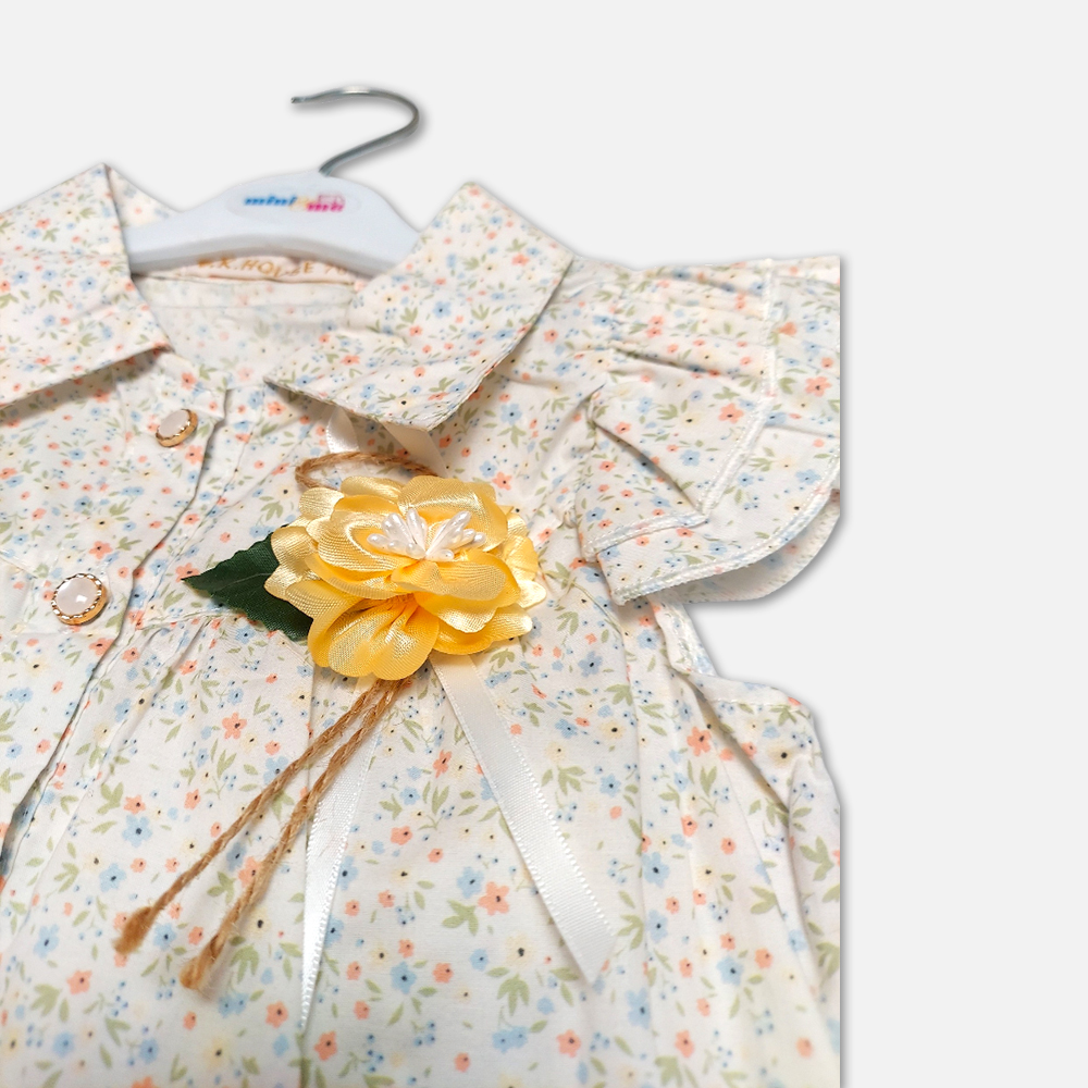 girlsSuit13134-2-5 A premium two-piece summer clothing set for baby girls featuring a cream button-down blouse with an all-over ditsy floral print, ruffle sleeves, and a yellow fabric flower brooch, alongside pastel yellow shorts with matching floral side panels, displayed on a hanger.