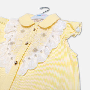 A premium two-piece summer outfit for baby girls consisting of a yellow and white pinstriped button-down blouse with a white lace embroidered bib and tie-front knot, paired with a pleated navy blue skirt featuring horizontal yellow stripes and a metallic gold belt, shown on a white hanger.