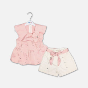 A premium two-piece formal outfit for baby girls featuring a sleeveless soft pink satin peplum top with a structured collar, scattered rhinestones, and a fabric flower brooch, paired with cream-colored shorts with rhinestone accents and a pink ribbon waist tie, displayed on a white hanger.